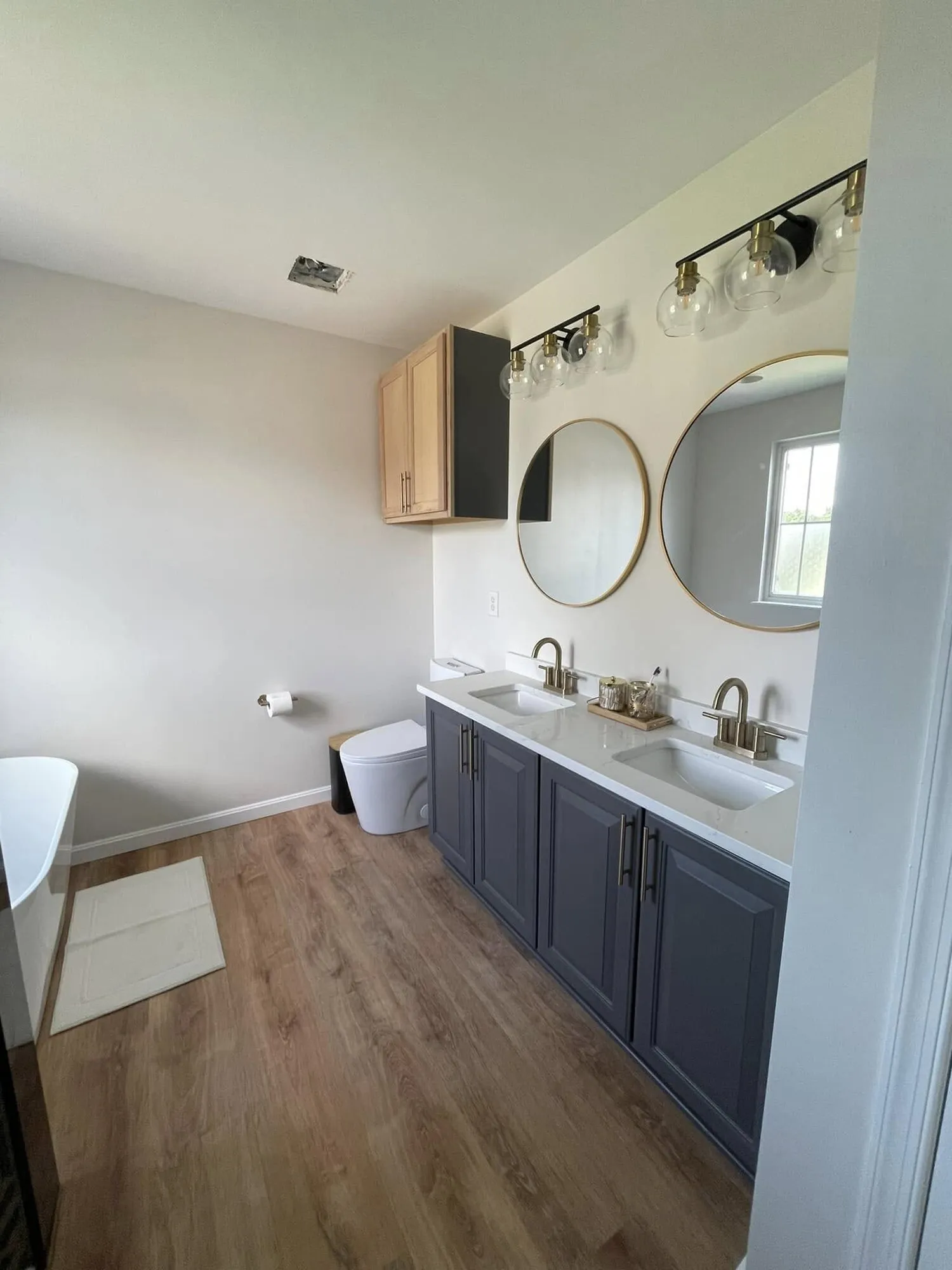 Bathroom with a navy painted vanity, brass fixtures and round mirrors