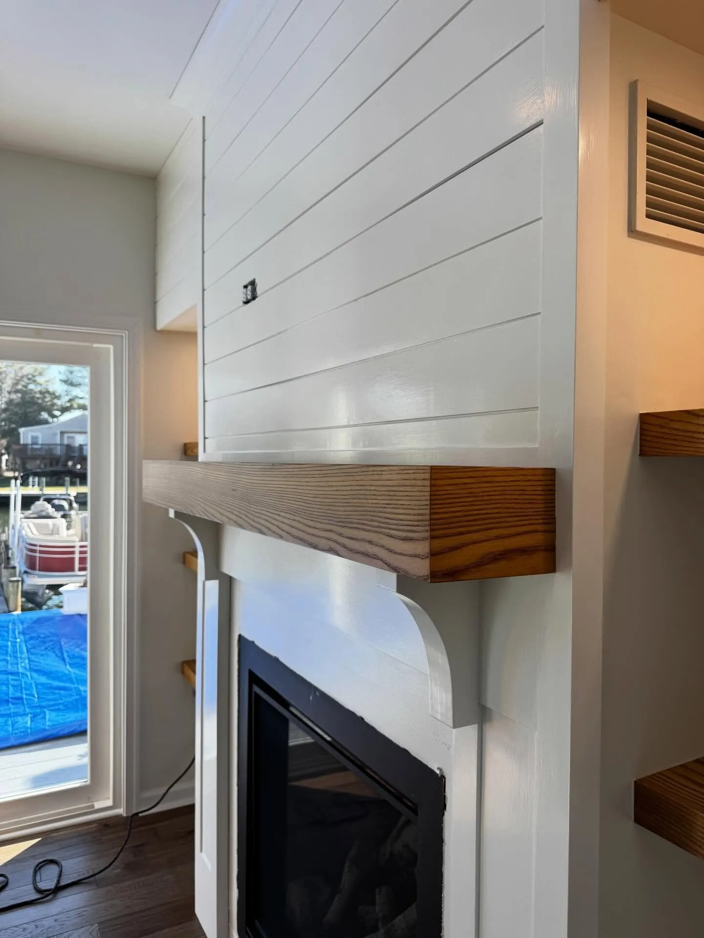 Close-up of a painted shiplap fireplace surround with a stained mantel