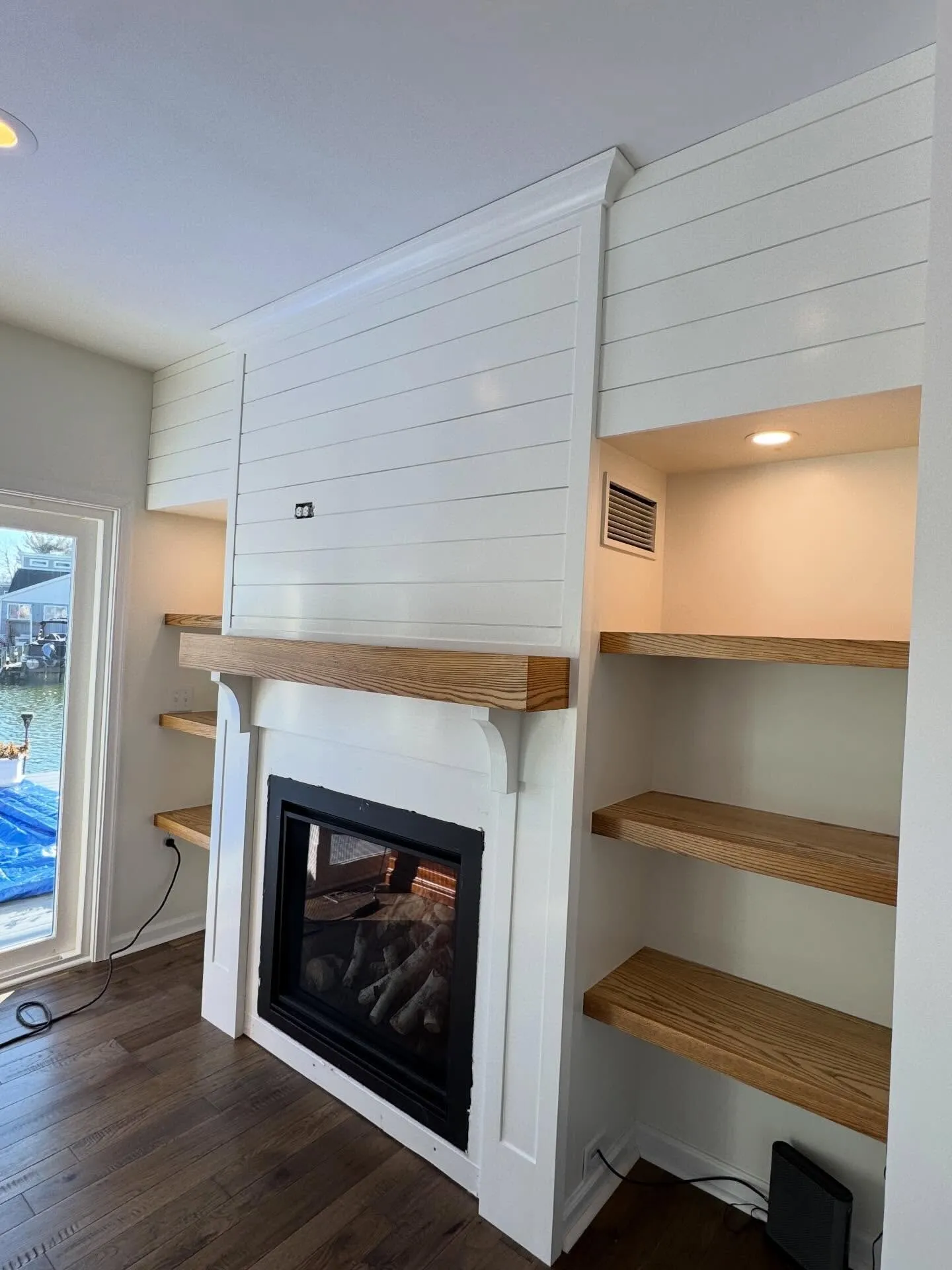 After: shiplap fireplace wall painted crisp white with a stained wood mantel and shelves