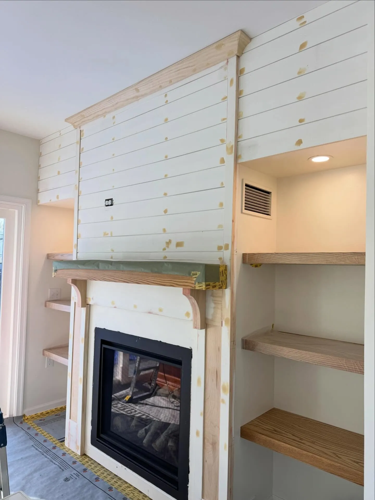 Before: raw shiplap fireplace wall with patched nail holes and an unfinished mantel