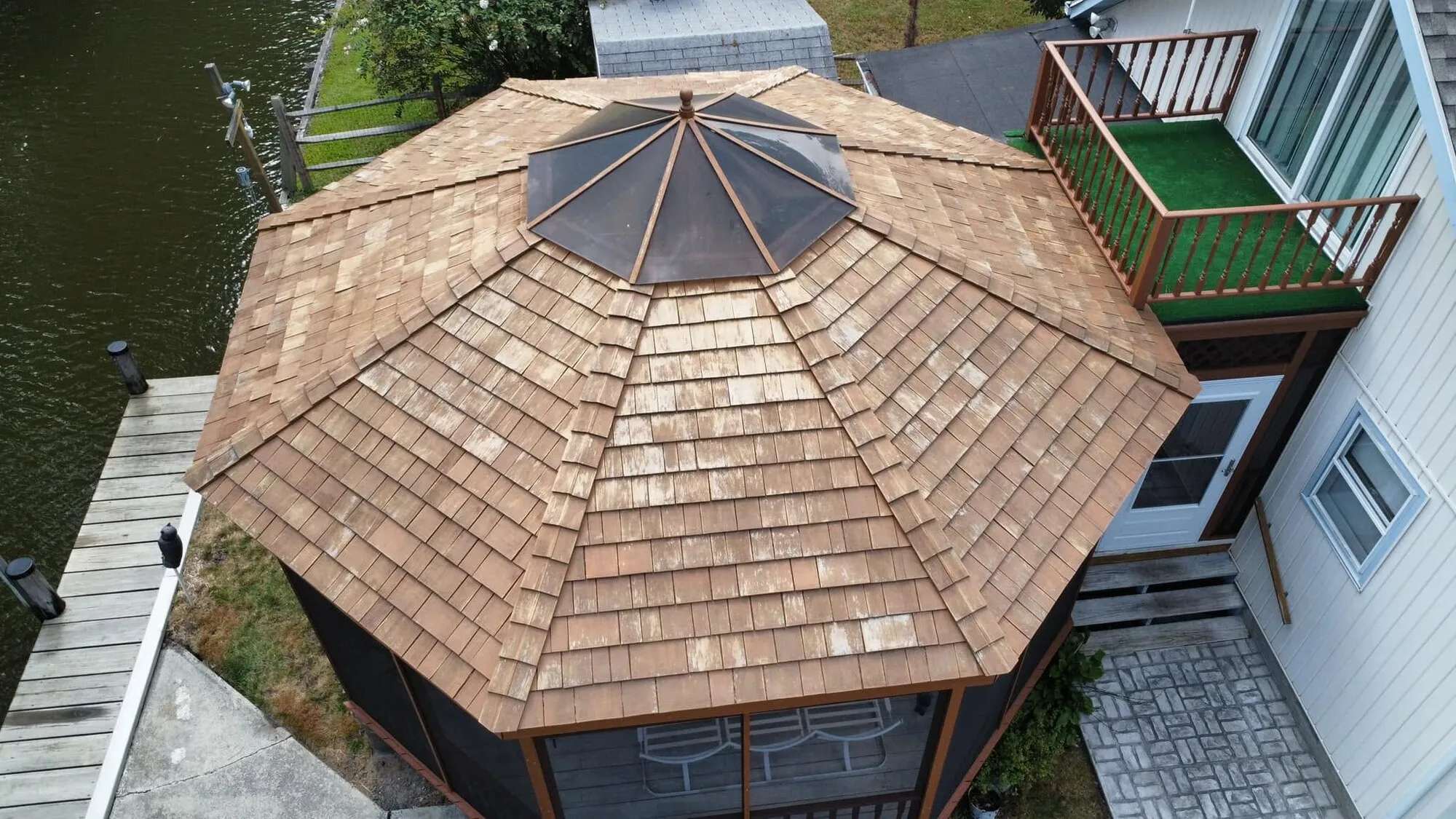 Before: aerial view of a weathered cedar shake gazebo roof on the water