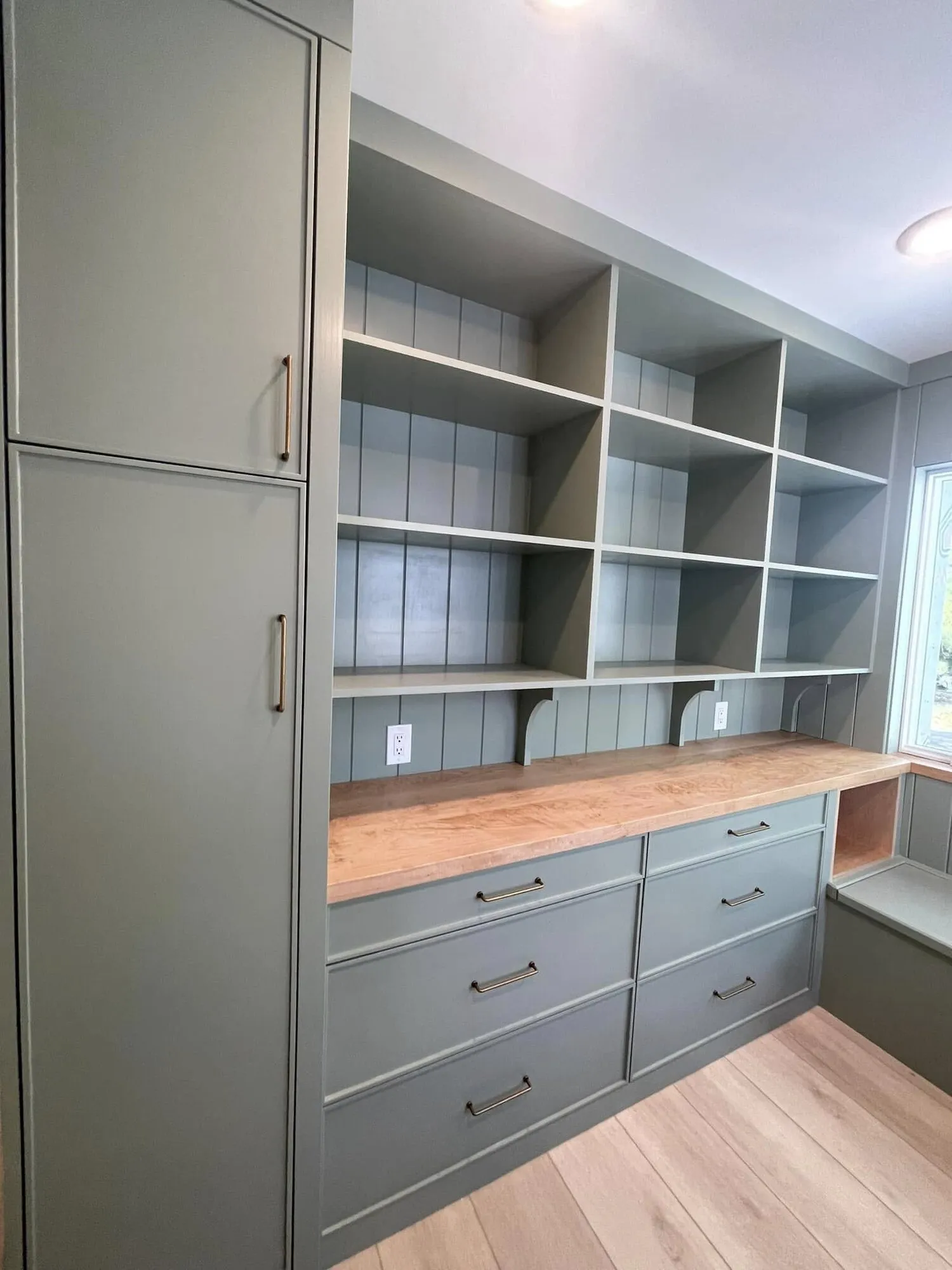 Built-in shelving and drawers painted green with wood countertops