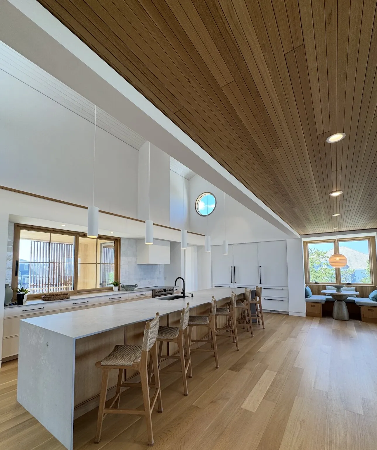 Open kitchen with crisp white walls beneath a natural wood plank ceiling