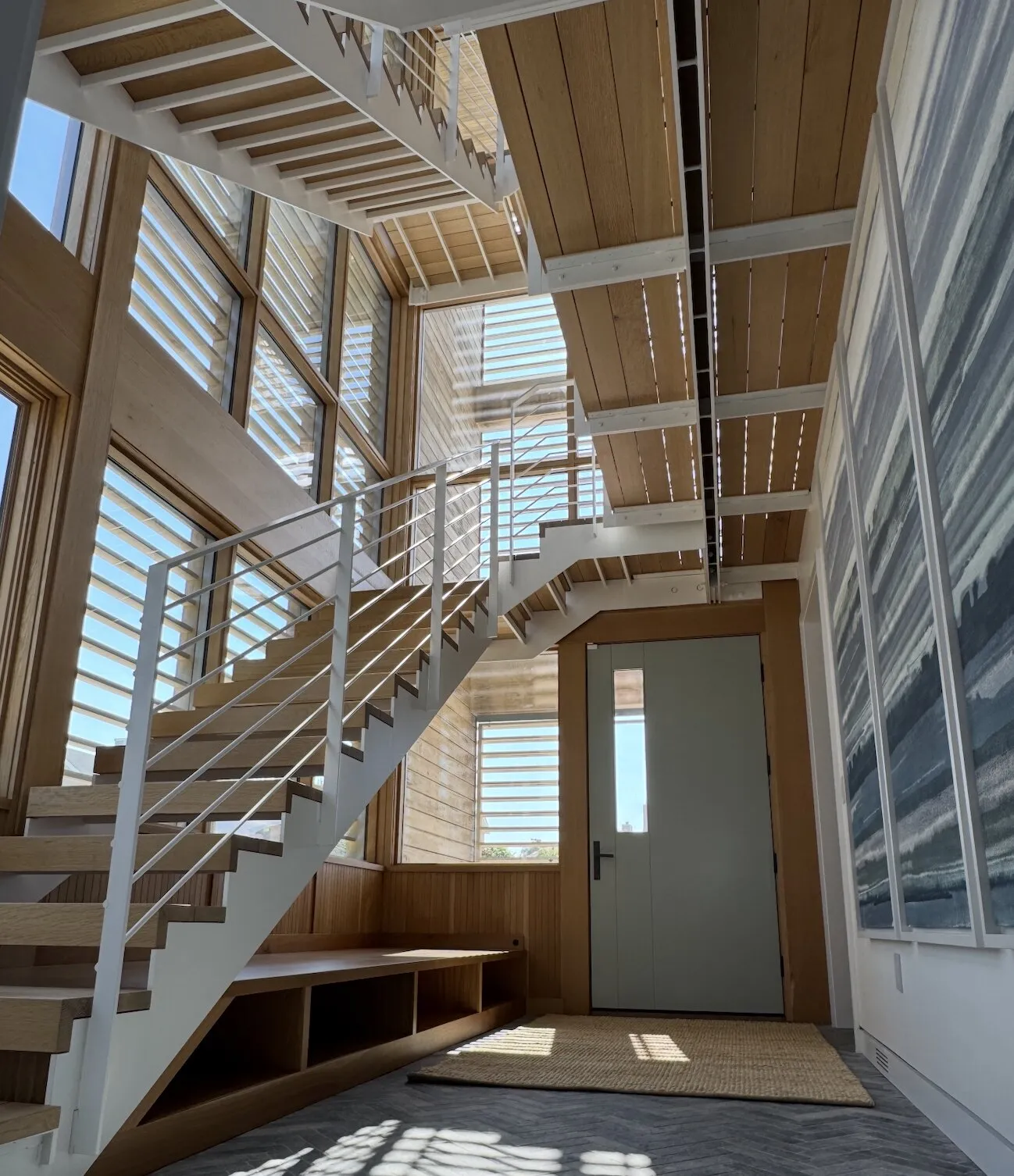Modern open staircase with white painted steel railings and natural wood