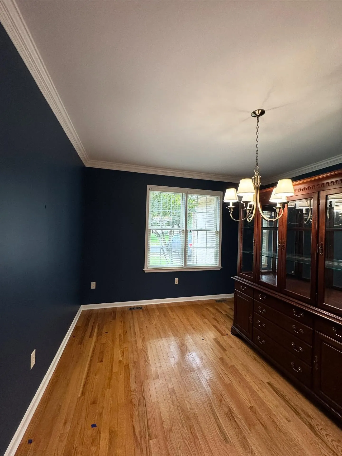 Dining room transformed with deep navy walls and bright white crown moulding