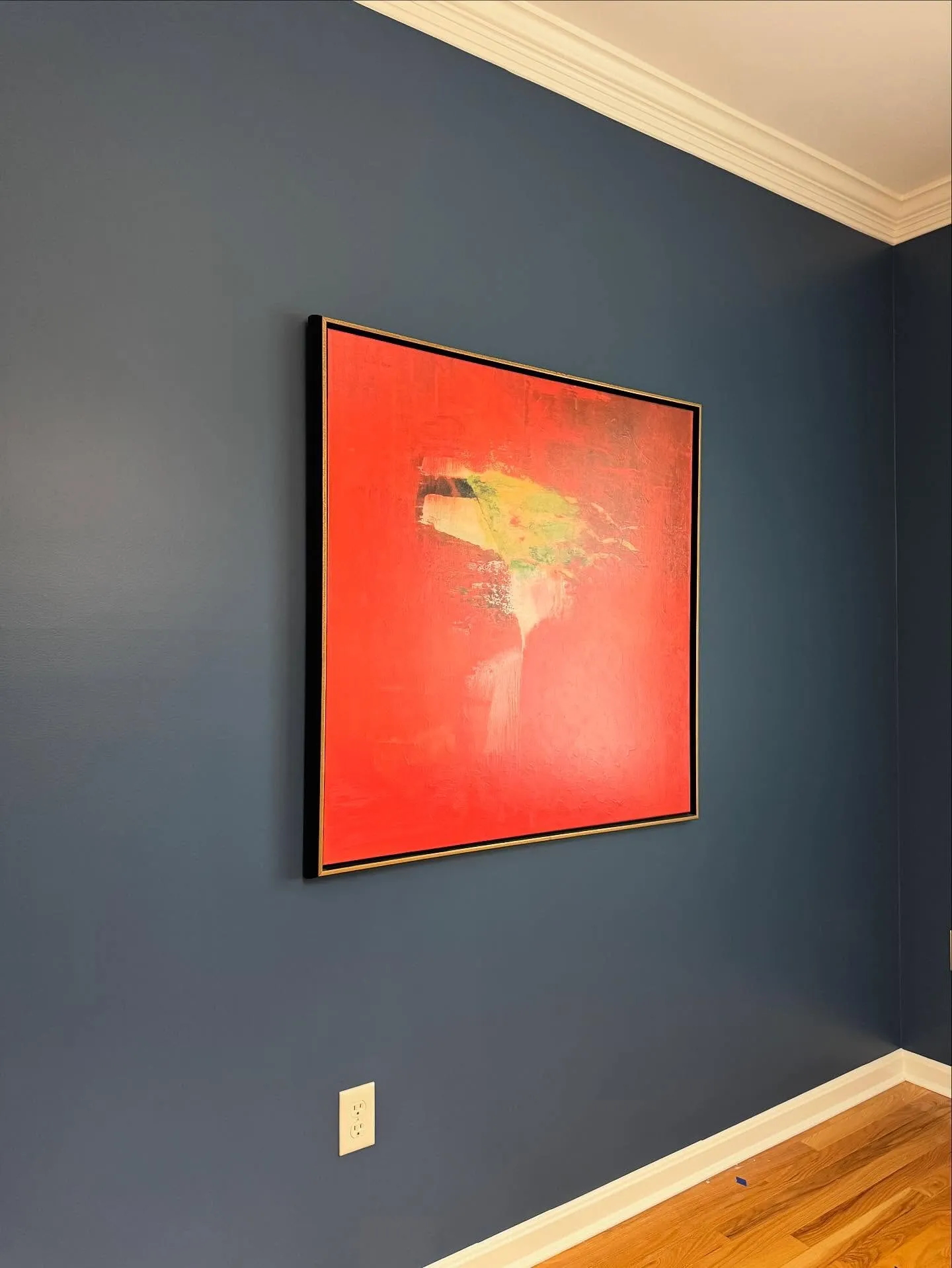 Deep navy accent wall with crisp white ceiling line and a red abstract painting